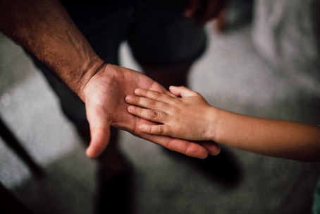 child putting hand on parent's hand
