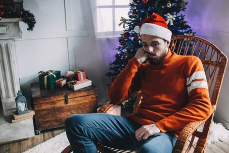 Man with santa hat on looking sad in chair